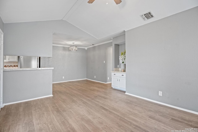 unfurnished living room with vaulted ceiling, ornamental molding, ceiling fan with notable chandelier, and light wood-type flooring