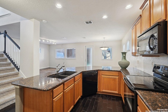 kitchen with dark wood-type flooring, sink, dark stone countertops, kitchen peninsula, and black appliances