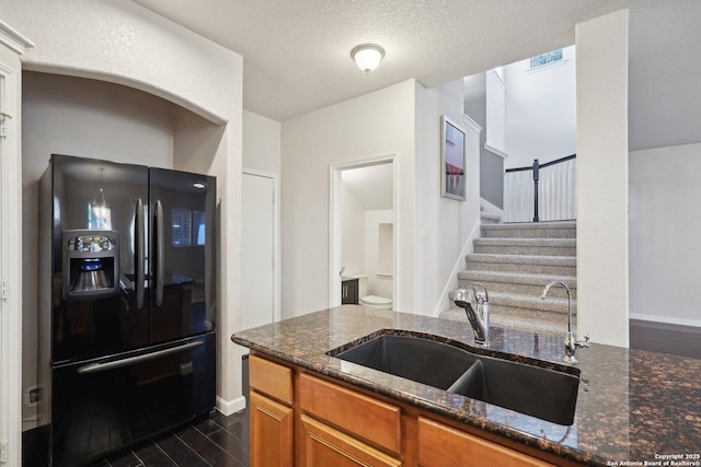 kitchen with black fridge, dark hardwood / wood-style floors, sink, and dark stone countertops