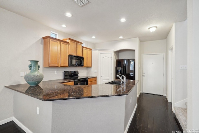 kitchen featuring dark hardwood / wood-style flooring, sink, black appliances, and kitchen peninsula