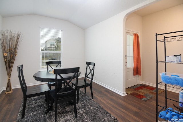 dining area with dark wood-type flooring and vaulted ceiling