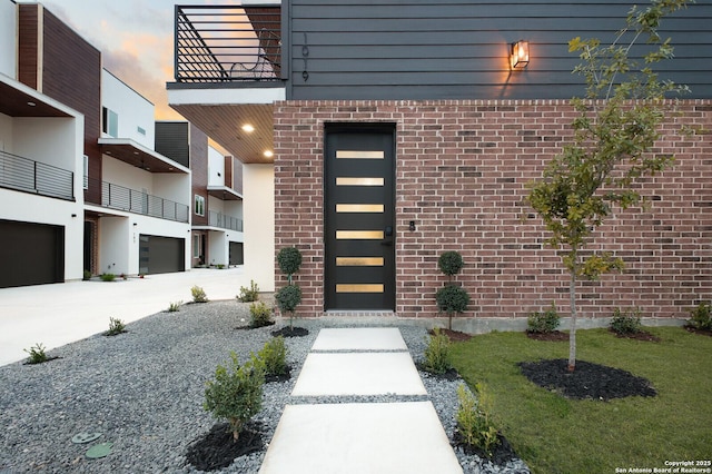 exterior entry at dusk with a garage and a balcony