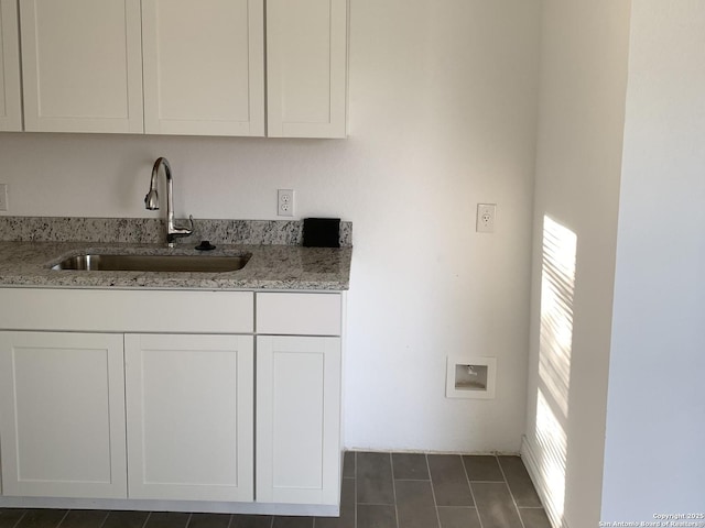 kitchen with light stone counters, sink, and white cabinets