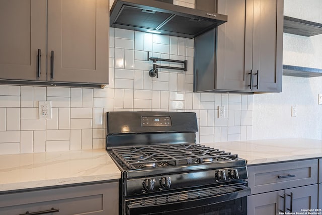 kitchen featuring wall chimney range hood, black range with gas stovetop, and gray cabinets