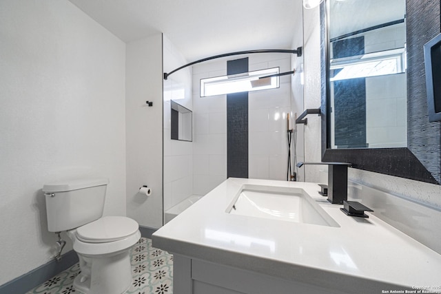 bathroom featuring vanity, toilet, and a tile shower