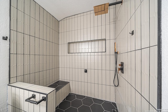 bathroom featuring a textured ceiling and a tile shower