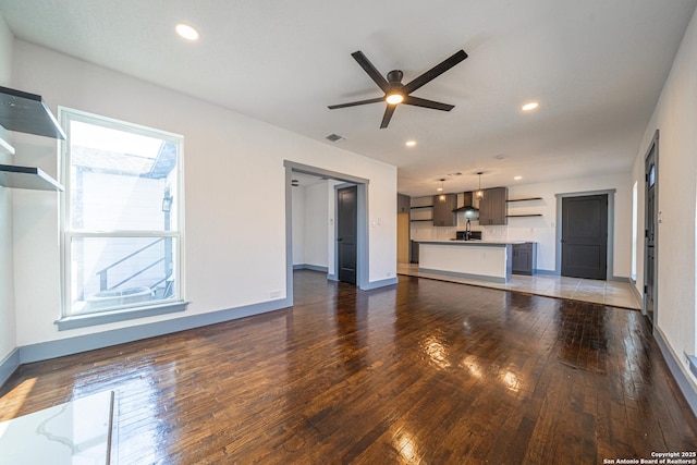 unfurnished living room featuring ceiling fan and dark hardwood / wood-style floors