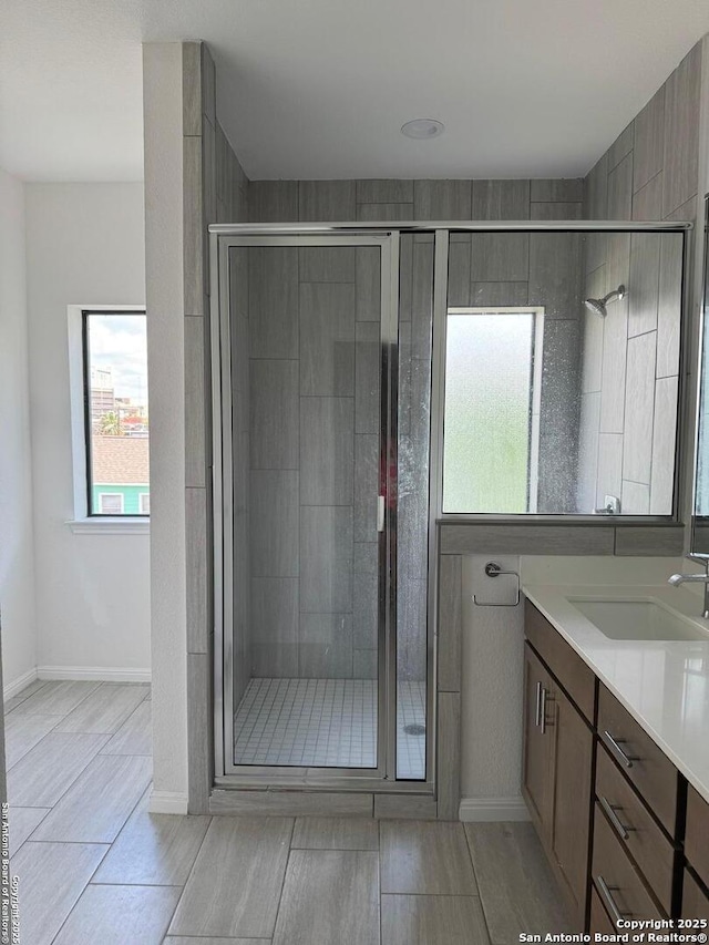 full bath featuring a shower stall, vanity, and baseboards