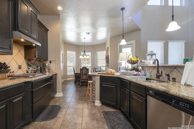 kitchen with pendant lighting, appliances with stainless steel finishes, light stone countertops, and sink