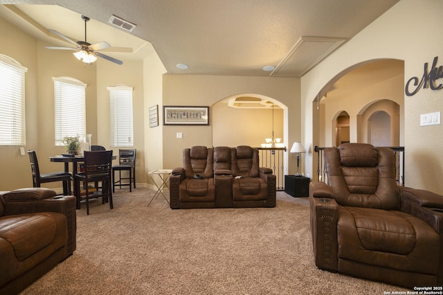 carpeted living room with ceiling fan with notable chandelier