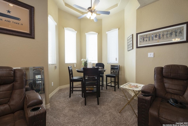 dining room with ceiling fan, a raised ceiling, and carpet