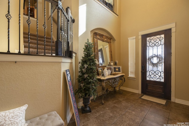 foyer entrance featuring dark tile patterned floors and a towering ceiling