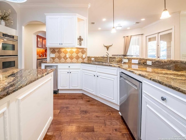 kitchen featuring pendant lighting, dark hardwood / wood-style flooring, white cabinets, and appliances with stainless steel finishes