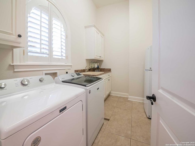 laundry area with cabinets, washer and dryer, sink, and light tile patterned floors