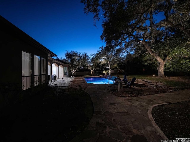 pool at dusk featuring a patio area