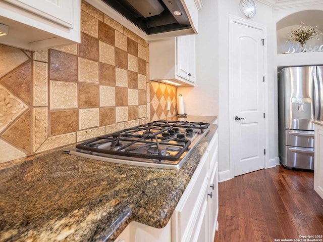 kitchen featuring white cabinetry, dark stone countertops, stainless steel appliances, dark hardwood / wood-style flooring, and decorative backsplash