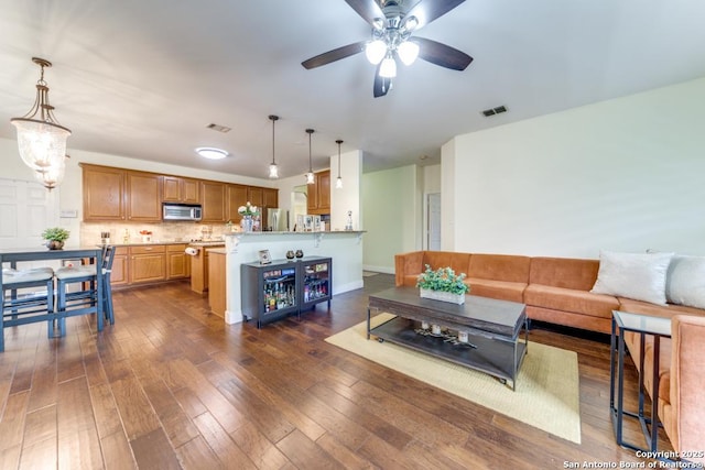 living room with dark hardwood / wood-style flooring and ceiling fan with notable chandelier