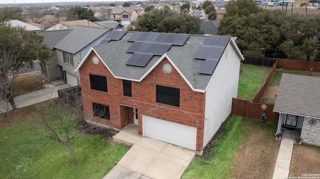 view of front of property with a garage, a front lawn, and solar panels