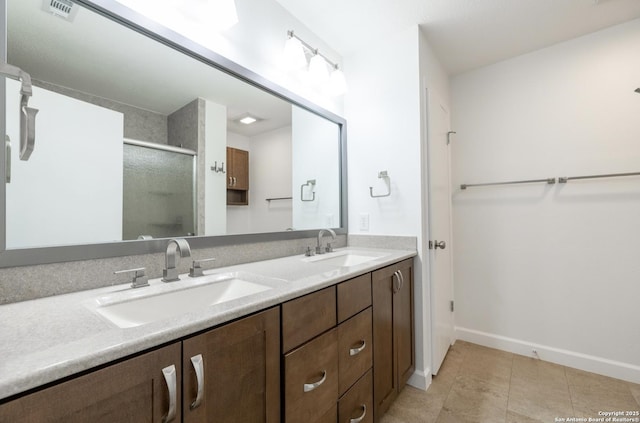 bathroom with a shower with door, vanity, and tile patterned floors