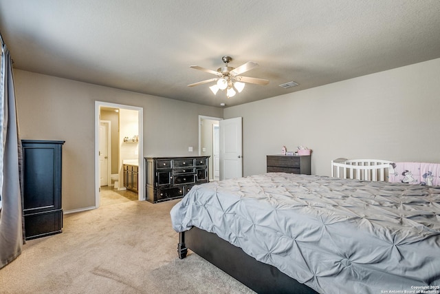 bedroom with ensuite bathroom, light carpet, ceiling fan, and a textured ceiling