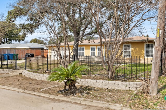 ranch-style house featuring a fenced front yard and stucco siding