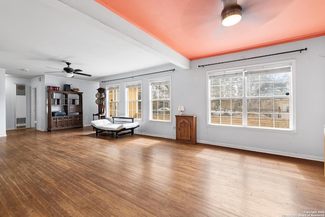 unfurnished living room with ceiling fan, beam ceiling, baseboards, and wood finished floors