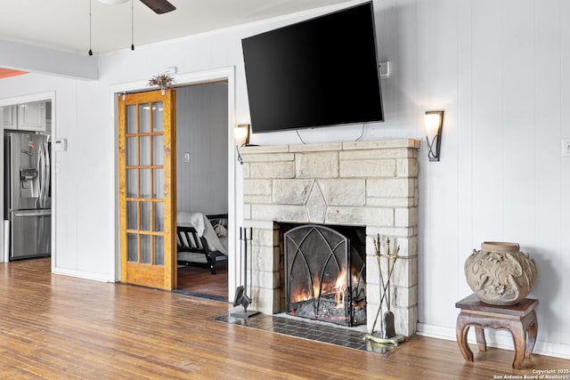 living area with a fireplace, a ceiling fan, wood finished floors, and ornamental molding