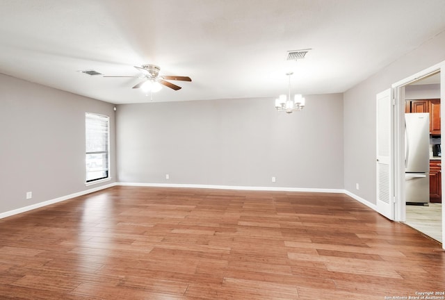 unfurnished room with ceiling fan with notable chandelier and light hardwood / wood-style floors