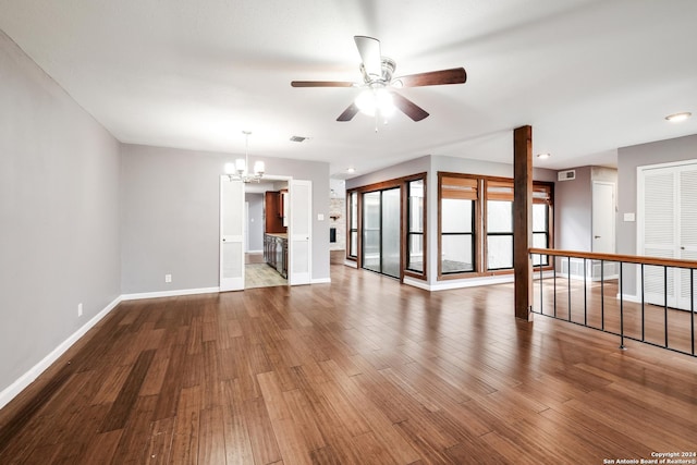 empty room with ceiling fan with notable chandelier and hardwood / wood-style floors