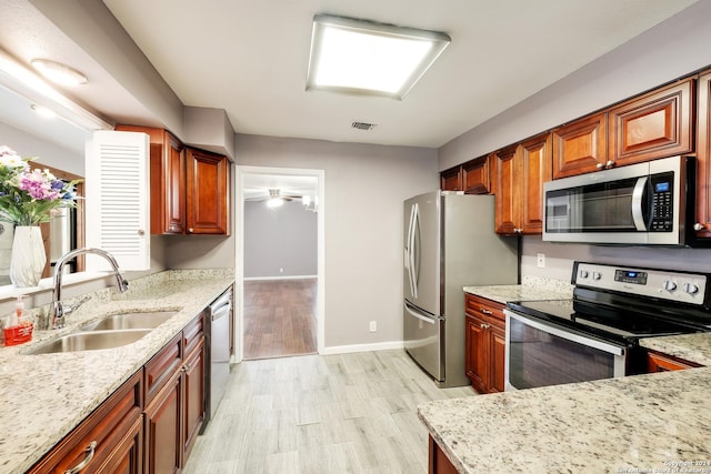 kitchen featuring sink, light hardwood / wood-style flooring, stainless steel appliances, and light stone countertops