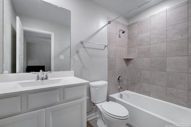 full bathroom featuring vanity, tiled shower / bath combo, and toilet