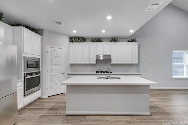 kitchen with sink, white cabinetry, stainless steel appliances, a center island with sink, and light wood-type flooring