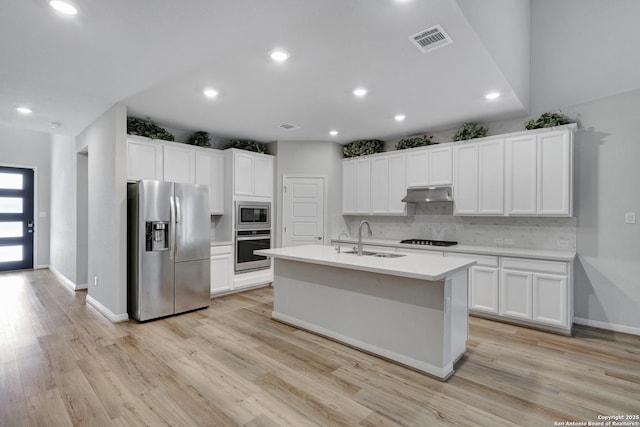 kitchen with sink, white cabinets, decorative backsplash, a kitchen island with sink, and stainless steel appliances