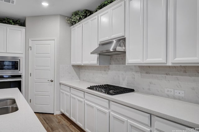 kitchen featuring backsplash, appliances with stainless steel finishes, light wood-type flooring, and white cabinets