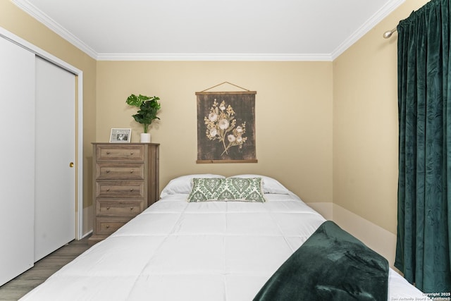 bedroom with hardwood / wood-style flooring, ornamental molding, and a closet