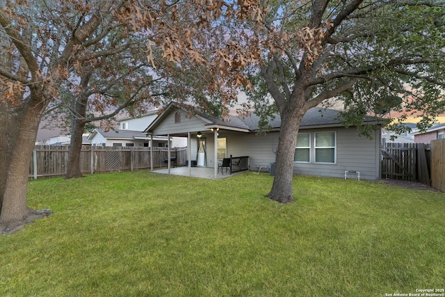 back house at dusk featuring a lawn and a patio