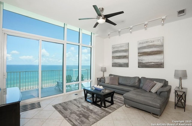 living room featuring a water view, ceiling fan, floor to ceiling windows, and light tile patterned floors