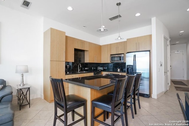 kitchen featuring a breakfast bar, tasteful backsplash, a kitchen island, pendant lighting, and stainless steel appliances