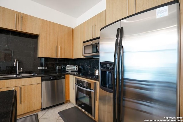 kitchen featuring sink, appliances with stainless steel finishes, dark stone countertops, tasteful backsplash, and light tile patterned flooring