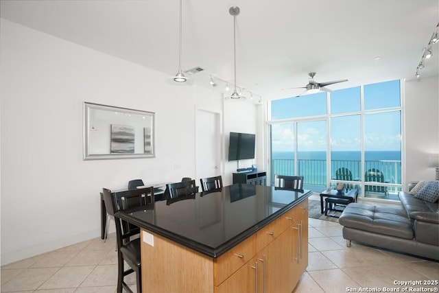 kitchen with rail lighting, light tile patterned floors, a kitchen island, pendant lighting, and a wall of windows