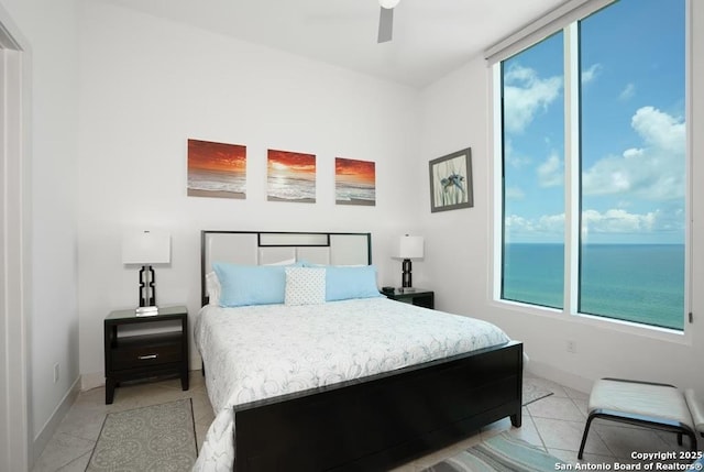 tiled bedroom with ceiling fan and a water view