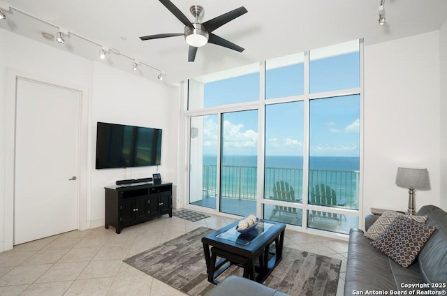 tiled living room featuring ceiling fan, a wall of windows, and rail lighting