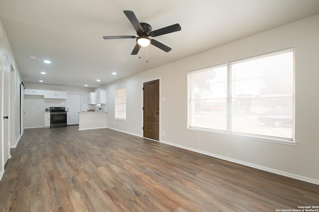 unfurnished living room featuring dark wood-type flooring and ceiling fan