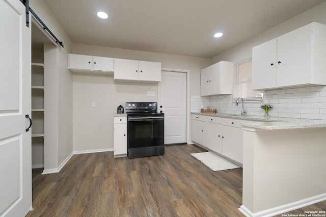 kitchen featuring white cabinetry, electric range oven, dark hardwood / wood-style flooring, decorative backsplash, and a barn door