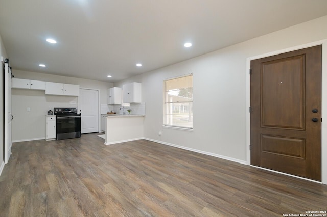 unfurnished living room featuring dark wood-type flooring and a barn door