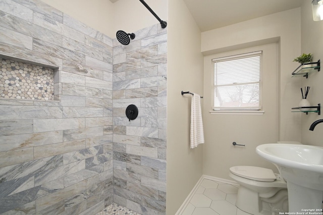 bathroom featuring tile patterned floors, toilet, sink, and a tile shower