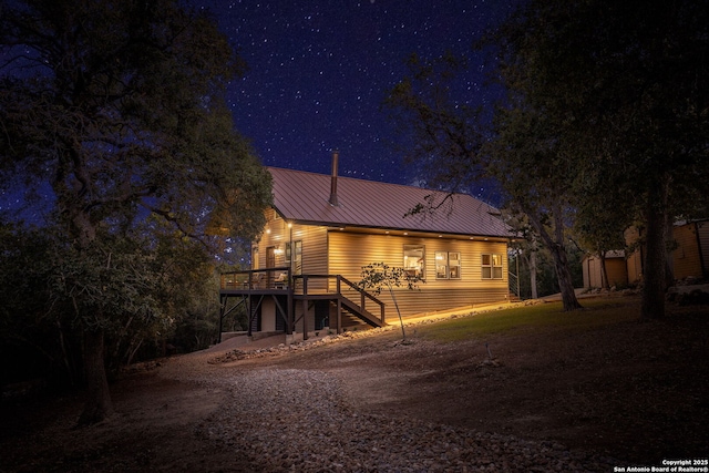 back house at twilight with a wooden deck