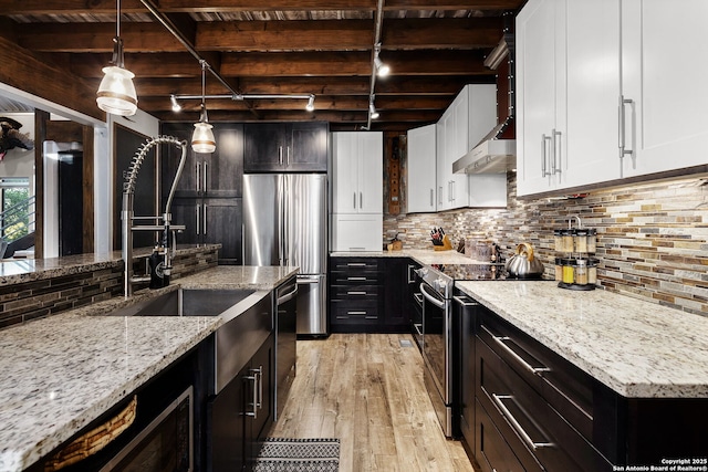 kitchen with tasteful backsplash, stainless steel appliances, light stone counters, and hanging light fixtures