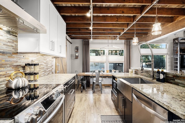 kitchen with white cabinetry, light stone counters, decorative light fixtures, ventilation hood, and appliances with stainless steel finishes