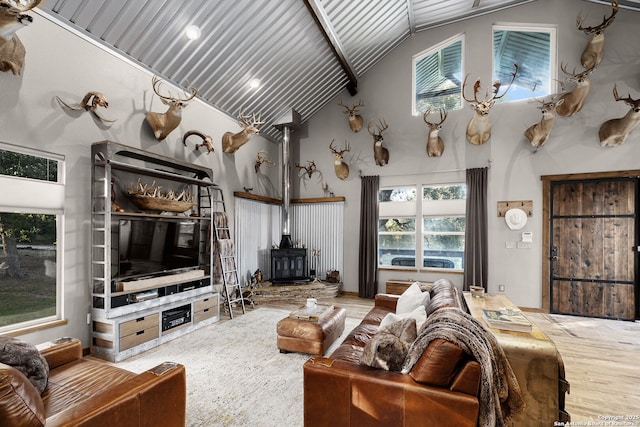 living room with hardwood / wood-style flooring, high vaulted ceiling, and a wood stove